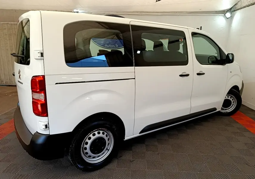 Vue 3/4 arrière droite d’un Peugeot Traveller blanc de 2018 avec vitres teintées et jantes acier noires.