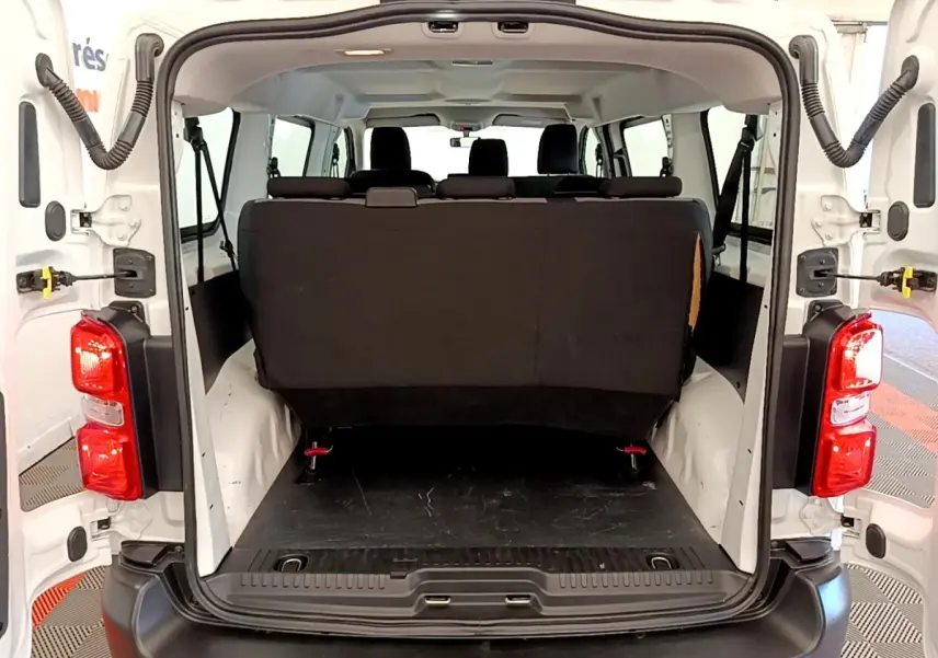 Vue arrière ouverte du Peugeot Traveller blanc 2018, montrant l'espace de chargement et la banquette arrière noire.