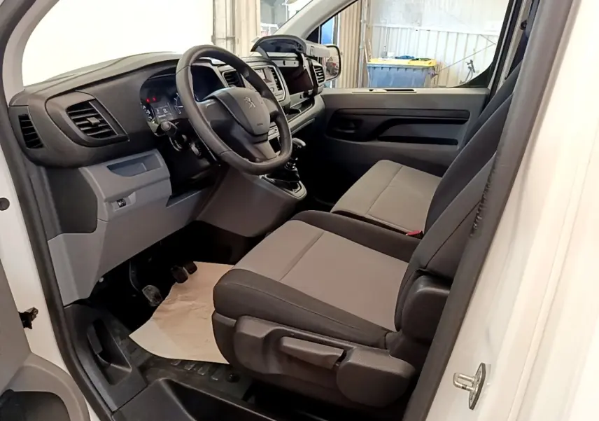 Vue intérieure côté gauche du Peugeot Traveller blanc 2018, montrant le tableau de bord et les sièges avant gris.