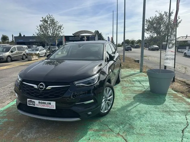 Vue 3/4 avant d’un Opel Grandland noir 2020, avec calandre distinctive et jantes argentées, stationné en extérieur.