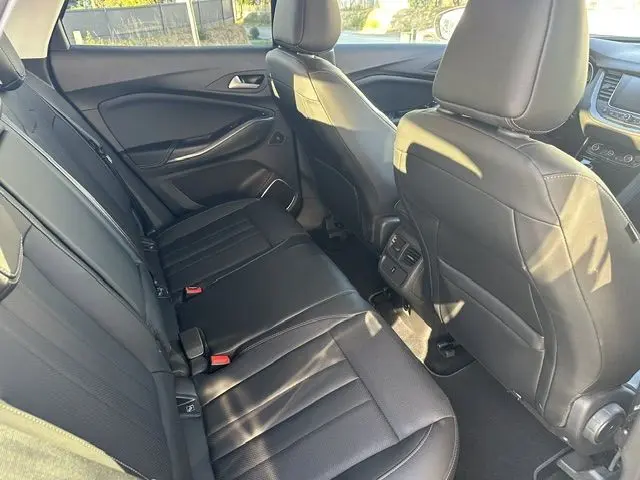 Vue intérieure arrière de l’Opel Grandland noire, montrant les sièges en cuir noir et la console centrale entre les sièges avant.