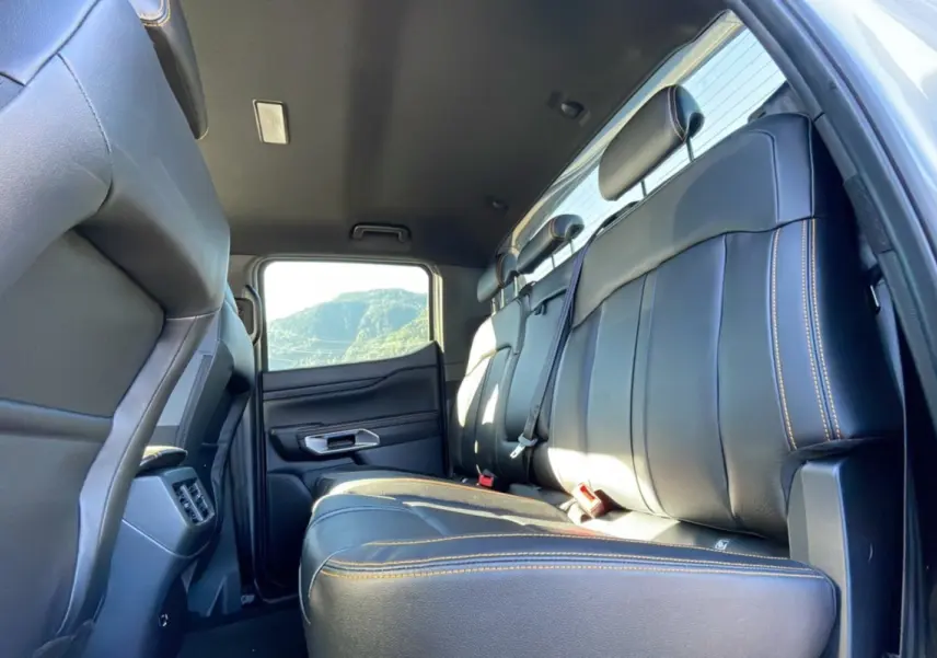 Vue intérieure arrière du Ford Ranger 2025 gris iconic, mettant en valeur les sièges en cuir noir avec surpiqûres orange.