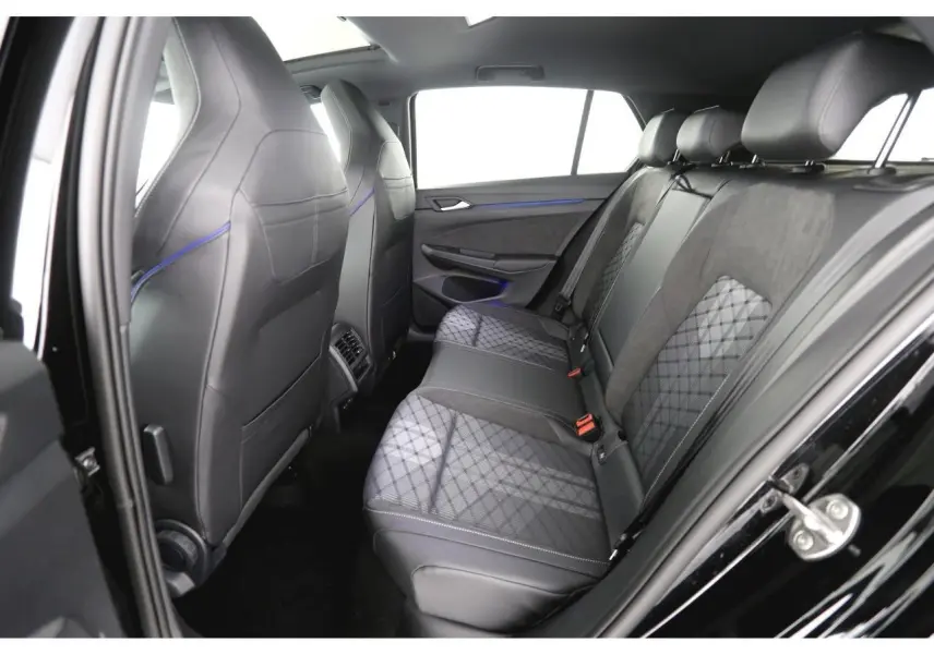 Vue côté droit de l’arrière intérieur de la Volkswagen Golf VIII avec sièges en tissu et cuir noir à motifs géométriques.