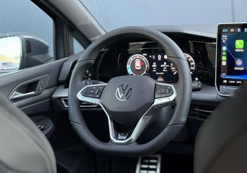 Vue intérieure centrée sur le volant cuir multifonctions de la Volkswagen Golf VIII avec tableau de bord digital.