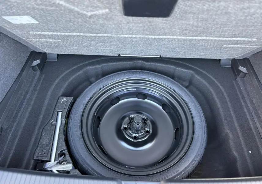 Gros plan sur la roue de secours noire dans le coffre d’une Volkswagen Golf VIII gris dauphin.