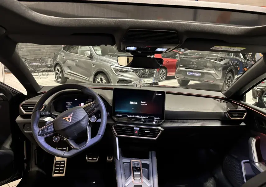 Vue intérieure avant du poste de conduite du CUPRA Leon 2026 avec volant cuir noir et écran tactile central.