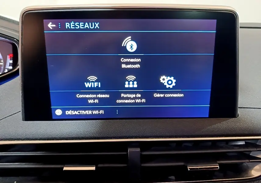 Écran tactile central affichant les options réseau Wi-Fi et Bluetooth dans le tableau de bord d’un Peugeot 3008 gris foncé.