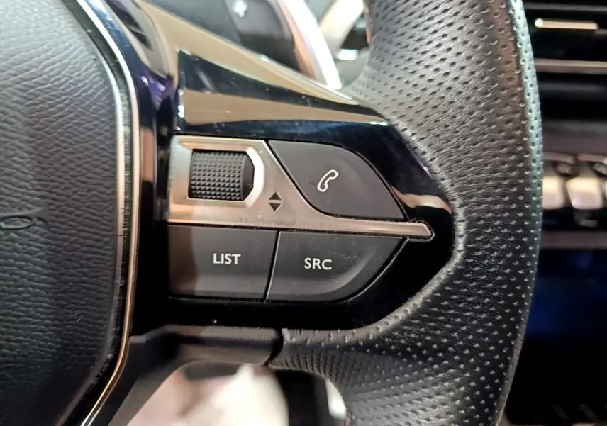 Gros plan sur les commandes gauche du volant cuir noir perforé du Peugeot 3008 GT Line gris foncé de 2020.