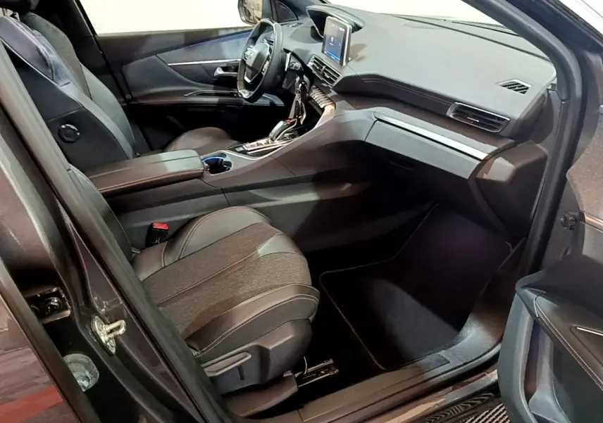 Vue intérieure côté passager avant du Peugeot 3008 gris foncé, avec tableau de bord moderne et sièges en cuir noir.