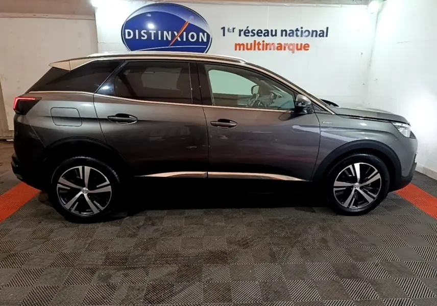 Profil droit d'un Peugeot 3008 gris foncé GT Line 2020 avec jantes alliage et toit noir dans un showroom.