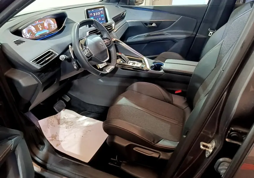 Intérieur avant droit du Peugeot 3008 gris foncé, volant cuir multifonctions et tableau de bord numérique lumineux.