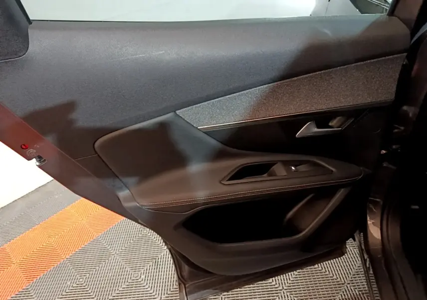 Porte arrière droite ouverte d’un Peugeot 3008 gris foncé, avec garniture intérieure noire et commande de vitre.