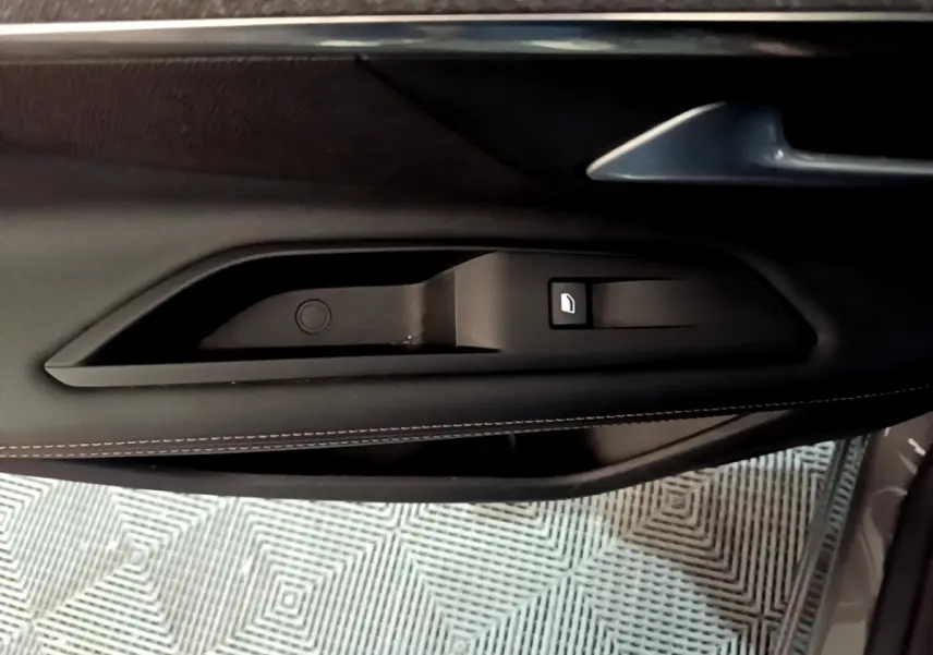 Gros plan sur la poignée intérieure de porte côté gauche en cuir noir avec surpiqûres contrastantes du Peugeot 3008 gris foncé.