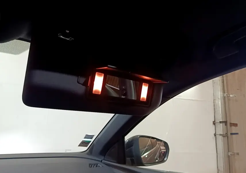 Détail du miroir de courtoisie éclairé sur le pare-soleil côté conducteur d’un Peugeot 3008 gris foncé.
