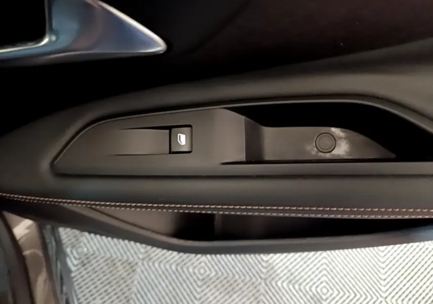 Gros plan sur la commande de lève-vitre côté conducteur du Peugeot 3008 gris foncé avec surpiqûres marron.