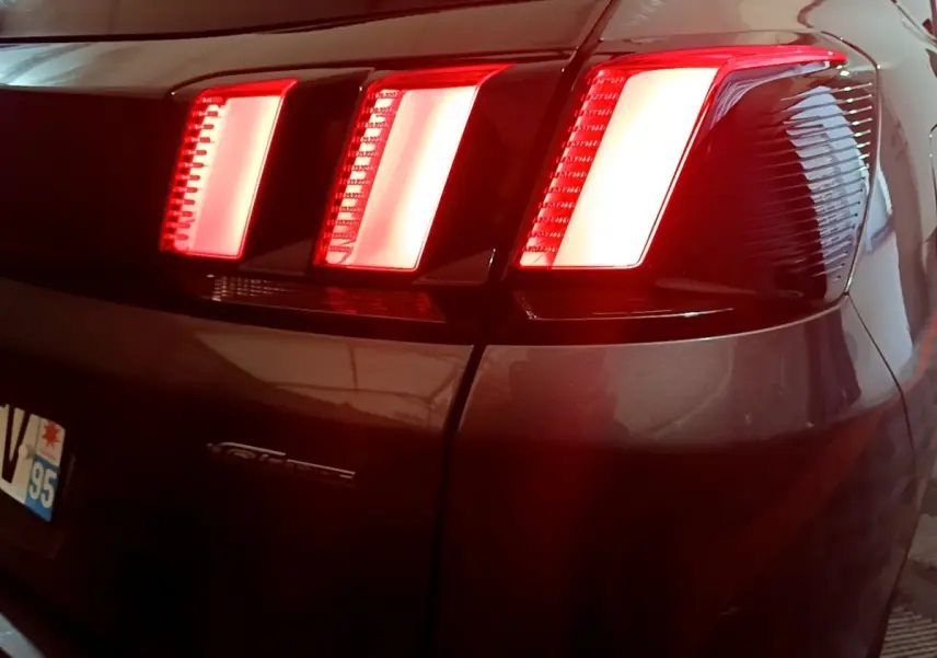 Feux arrière allumés en gros plan sur le côté droit d’un Peugeot 3008 GT Line gris foncé de 2020.