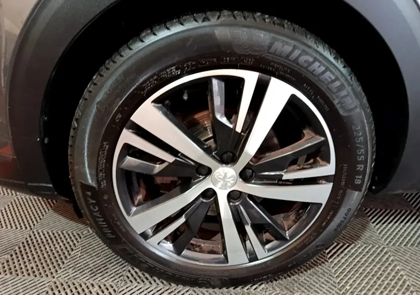 Gros plan sur la roue avant droite du Peugeot 3008 gris foncé, jante alliage bicolore et pneu Michelin.