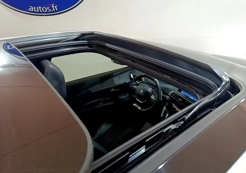 Vue plongeante sur l'intérieur du Peugeot 3008 gris foncé, mettant en valeur le volant cuir multifonctions et le tableau de bord digital.