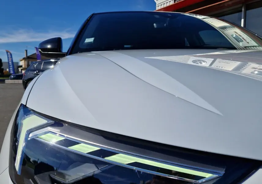 Gros plan sur le phare avant gauche de l'Audi A1 Sportback blanc glacier, soulignant ses LED distinctives et lignes anguleuses.