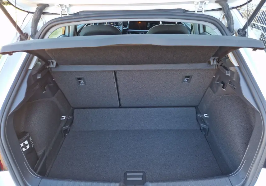 Vue intérieure du coffre ouvert d'une Audi A1 Sportback blanc glacier, montrant l'espace de rangement et la tablette arrière.