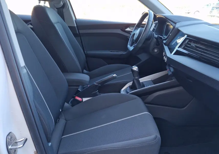 Vue intérieure côté gauche de l'Audi A1 Sportback blanc glacier 2020, montrant les sièges avant et la console centrale avec boîte manuelle.