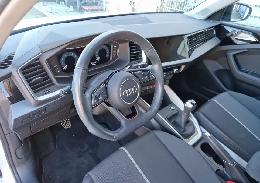 Vue intérieure côté conducteur de l'Audi A1 Sportback 25 TFSI 2020, volant cuir, tableau de bord numérique et boîte manuelle.