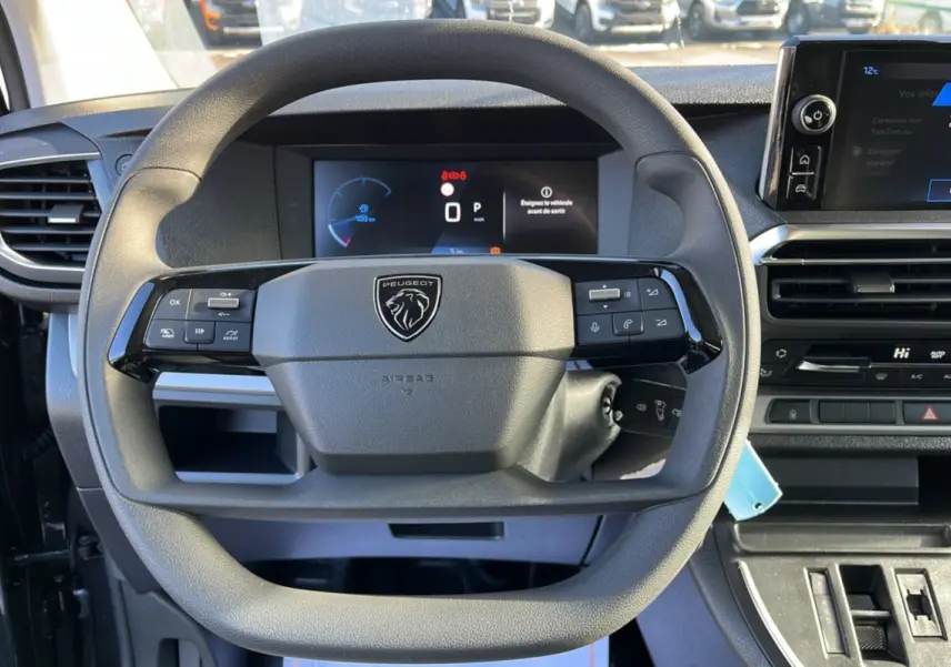 Vue rapprochée du volant multifonctions et du tableau de bord numérique du Peugeot Traveller 2025 gris titane.