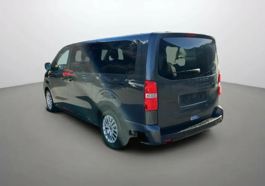 Vue 3/4 arrière droite d’un Peugeot Traveller gris titane avec vitres surteintées et portes latérales coulissantes.