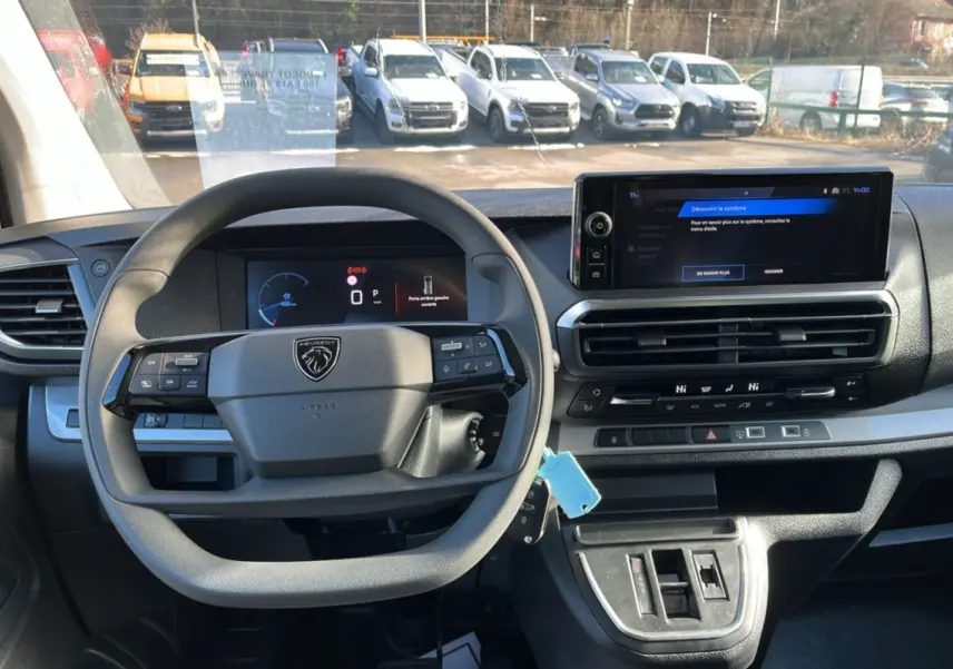 Vue intérieure du poste de conduite du Peugeot Traveller gris titane, avec volant multifonctions et écran tactile central.