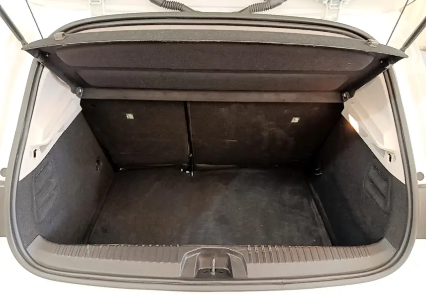 Coffre ouvert vu de face d’une Renault Clio Business Blue dCi 85 blanche, intérieur noir et espace de rangement visible.