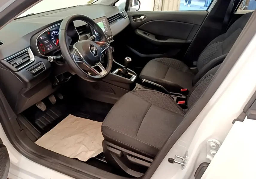 Intérieur de Renault Clio Business Blue dCi 85 blanc, vue côté conducteur, volant multifonction et sièges tissu noirs.