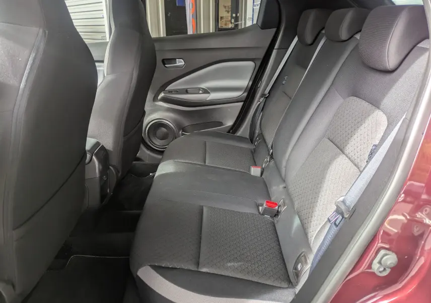 Vue intérieure arrière côté droit du Nissan Juke rouge 2020, montrant les sièges arrière en tissu noir avec motifs.