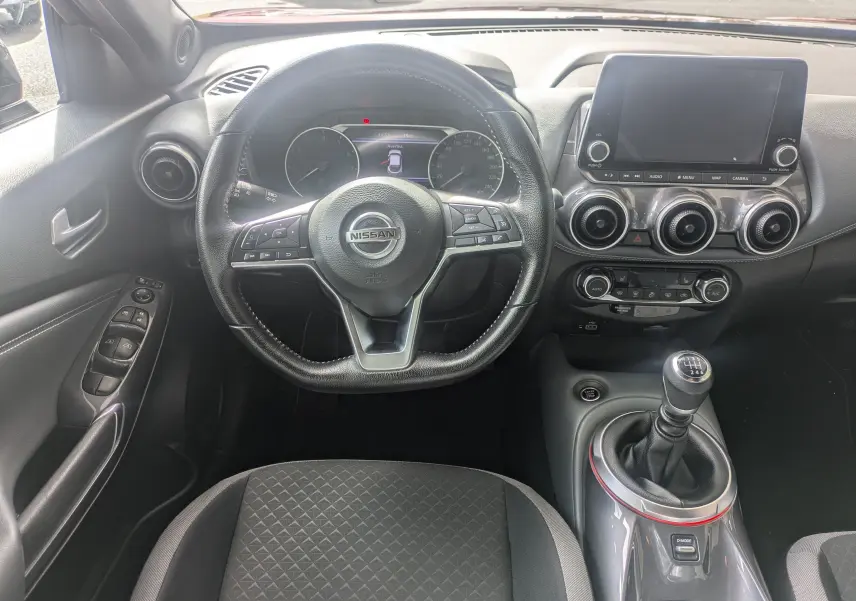 Vue intérieure centrée sur le volant et la console du Nissan Juke 2020, avec levier de vitesse manuel et écran tactile.