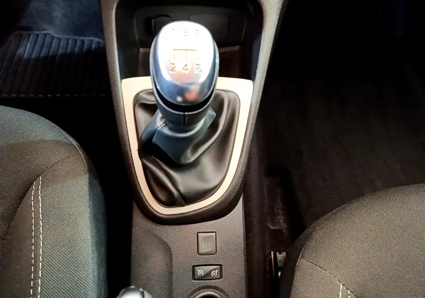 Le levier de vitesses manuel central de la Renault Captur Business gris foncé, entouré des sièges avant en tissu noir.