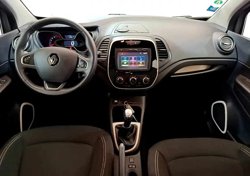 Vue frontale de l'habitacle du Renault Captur gris foncé 2018 avec volant cuir, écran tactile 7 pouces et boîte manuelle.
