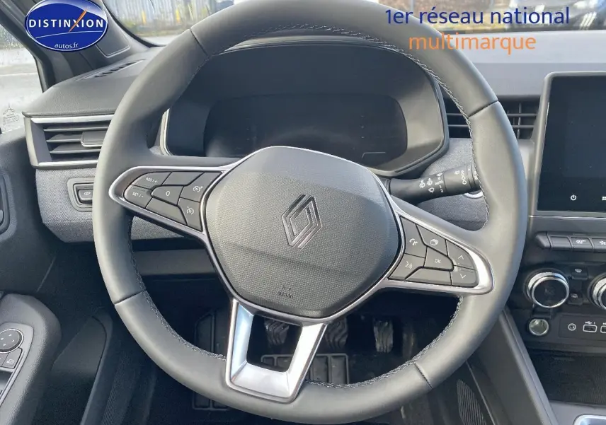 Vue intérieure centrée sur le volant multifonction noir de la Renault Clio V gris rafale avec tableau de bord et écran tactile.