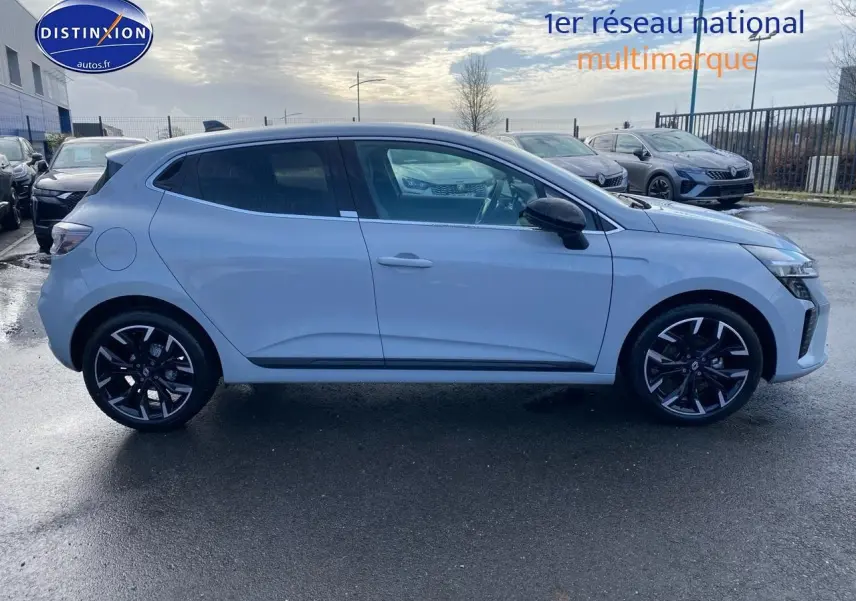 Profil droit d'une Renault Clio V gris rafale avec jantes alliage noires et rétroviseurs noirs, stationnée en extérieur.