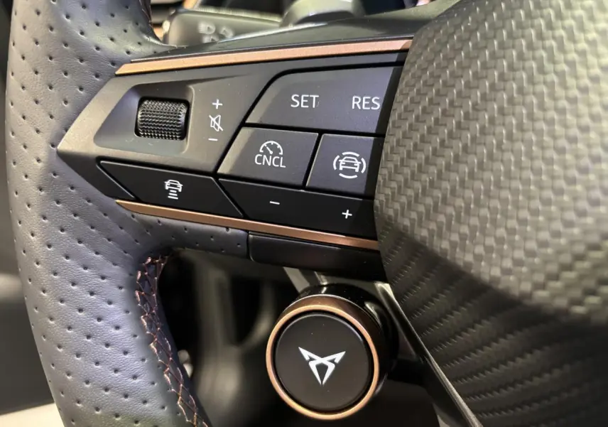 Gros plan sur le volant perforé noir avec surpiqûres cuivrées et commandes multifonctions du CUPRA Leon 2026.