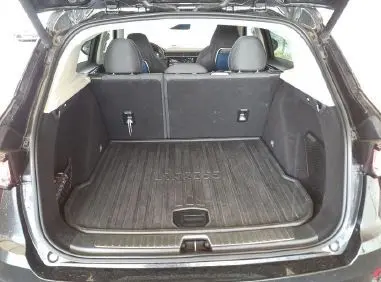 Coffre ouvert en vue arrière d'un Lynk & Co 01 noir, montrant l'espace de chargement et la banquette arrière.