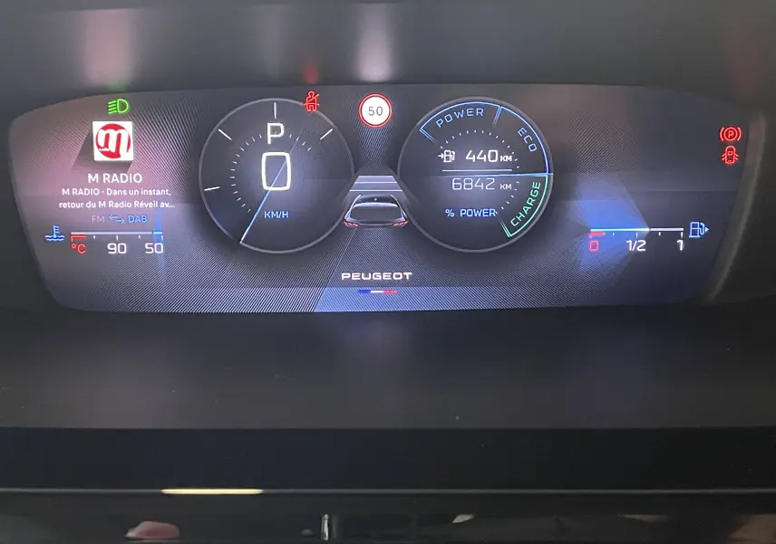 Tableau de bord numérique du Peugeot 308 Hybrid 145, affichant vitesse à zéro, autonomie et indicateurs de charge.