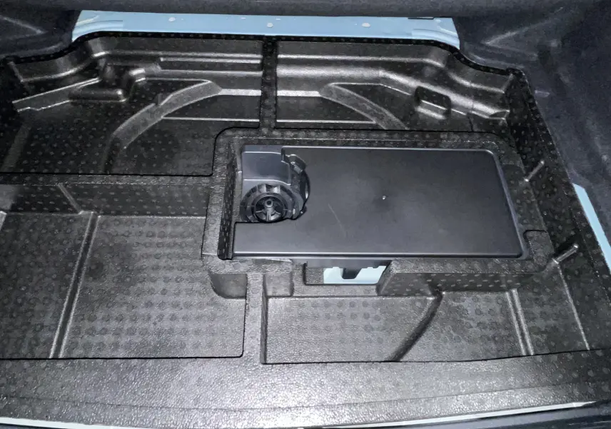 Vue rapprochée de l’espace de rangement sous le plancher de coffre d’une Peugeot 308 Hybrid 145 bleu obsession.