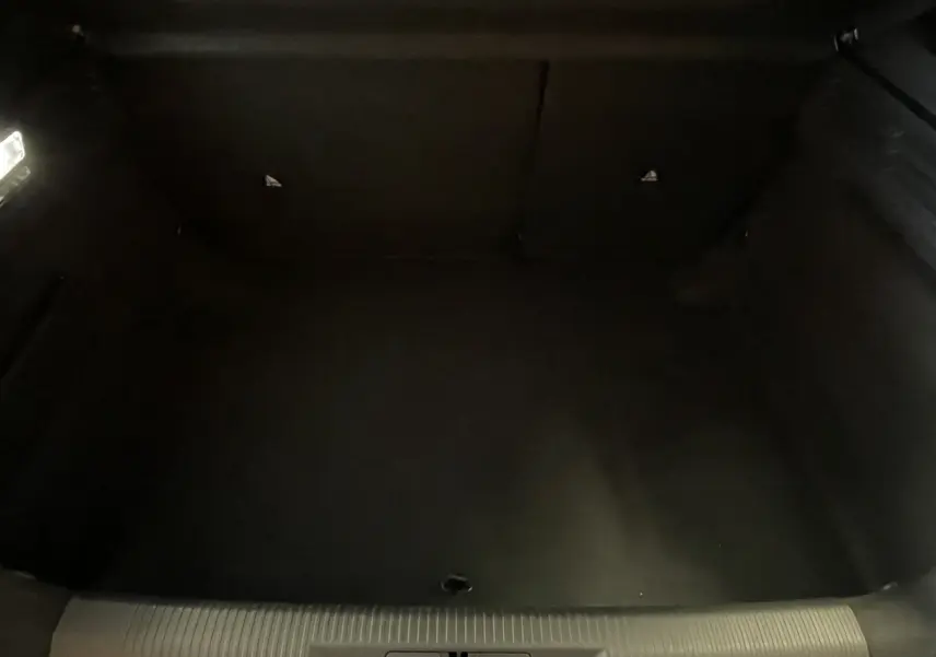 Coffre vide de Peugeot 308 Hybrid 145 e-DCS6 Allure, vue intérieure sombre sans objet visible.