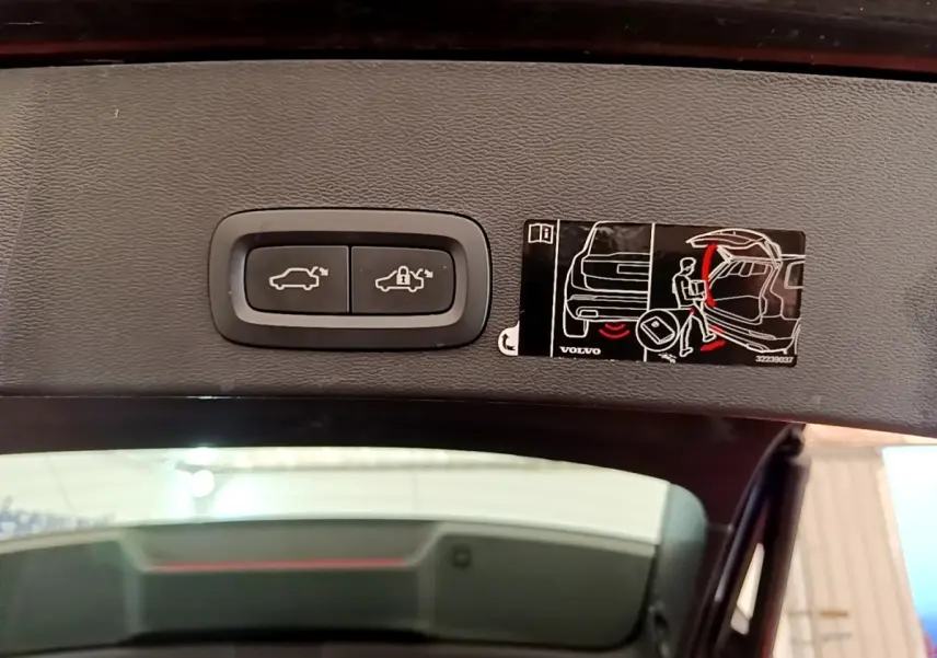 Gros plan sur les boutons d'ouverture et de verrouillage électrique du coffre du Volvo XC40 noir, vue intérieure du hayon ouvert.