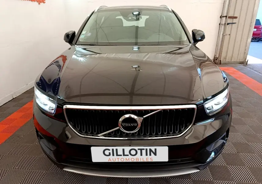 Vue avant d’un Volvo XC40 T2 noir avec calandre chromée et phares LED allumés dans un showroom.