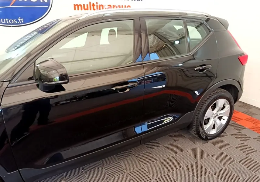 Vue latérale droite du Volvo XC40 noir 2020 avec jantes alliage et rétroviseurs électriques dans un showroom.