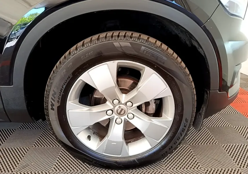 Gros plan sur la roue avant droite d’un Volvo XC40 noir, jante argentée à cinq branches, pneu hiver Pirelli.