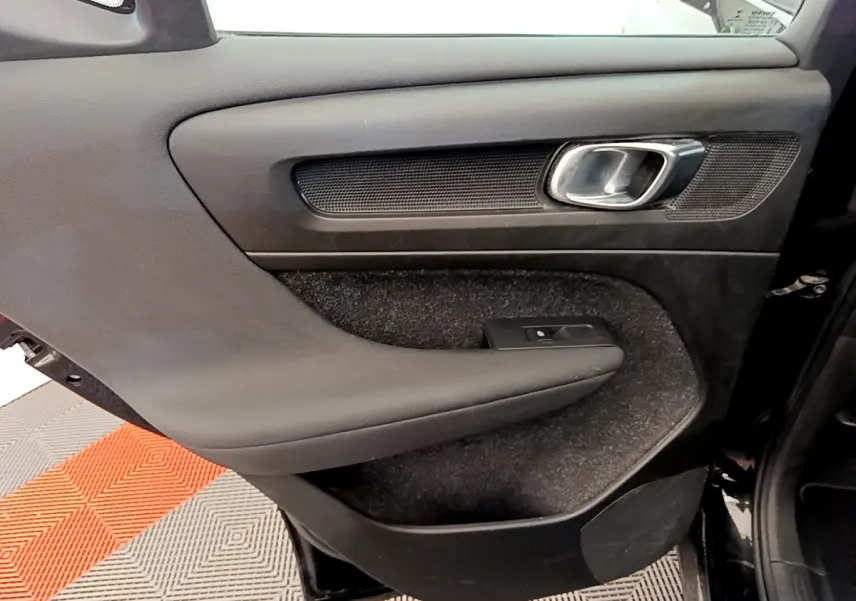 Gros plan sur la porte intérieure côté gauche noire du Volvo XC40 T2 Momentum avec poignée métal et commande de vitre.