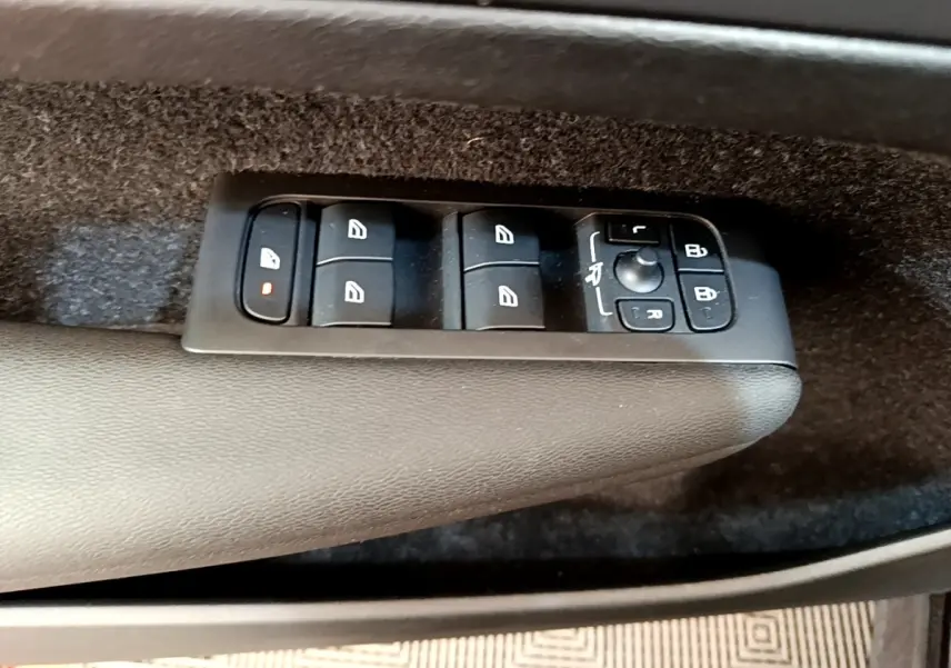 Gros plan sur les commandes de lève-vitres et rétroviseurs sur la porte intérieure côté conducteur d’un Volvo XC40 noir.