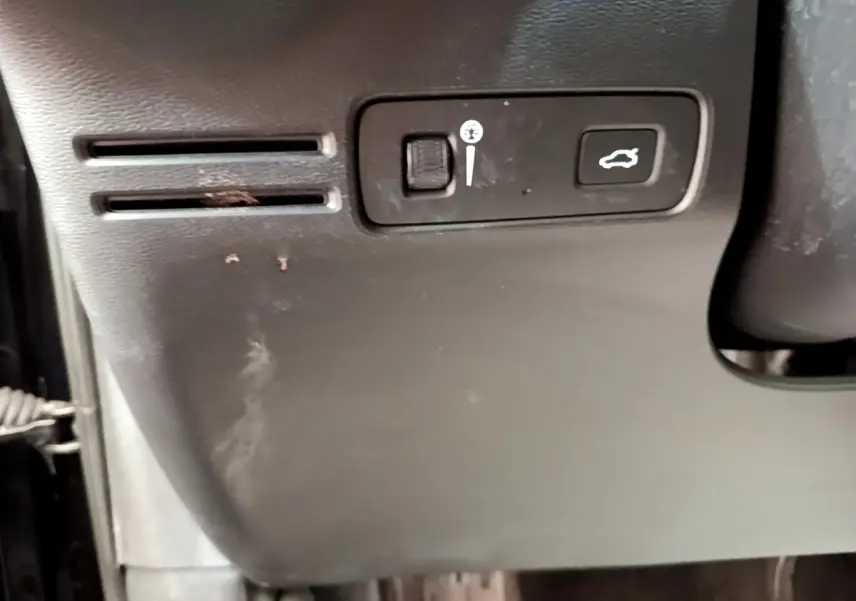 Détail intérieur montrant les commandes d'ouverture du coffre et réglage de luminosité sur un Volvo XC40 noir.