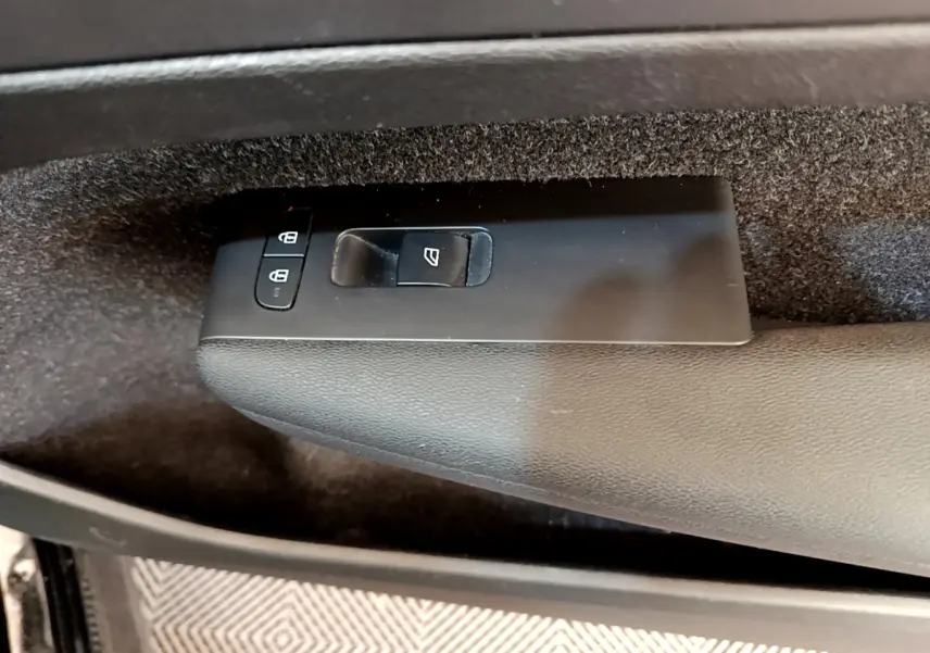Gros plan sur les commandes de lève-vitre et verrouillage sur la porte intérieure côté conducteur d’un Volvo XC40 noir.